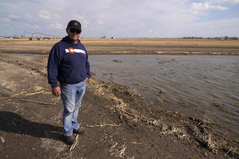 Don Schneider stands in front of an augmentation pond on his property Friday, April 29, 2022, in Ovid, Colo. He pumps water from a shallow aquifer for irrigation, and uses supply from the South Platte River to replenish the wells. (AP Photo/Brittany Peterson)