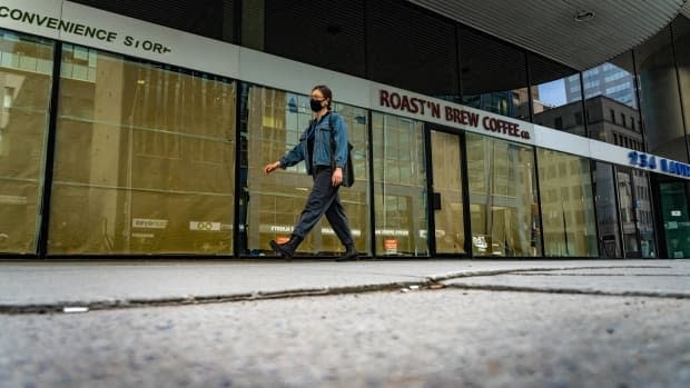 A masked person walks past a shuttered coffee shop in downtown Ottawa on May 11.