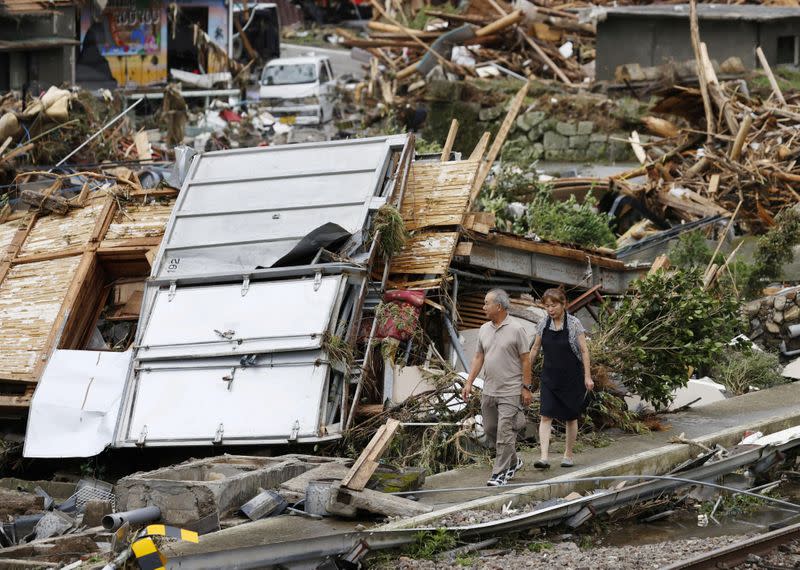 A couple looks around a site of their parent's house which was damaged by torrential rain in Kuma town