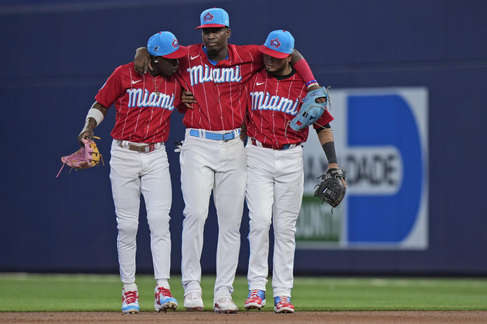 Miami Marlins center fielder Jazz Chisholm Jr., left, and second baseman Luis Arraez, right, help right fielder Jesus Sanchez off the field after Sanchez hurt himself making a diving catch of a ball hit by Cincinnati Reds' Tyler Stephenson during the first inning of a baseball game, Saturday, May 13, 2023, in Miami. (AP Photo/Wilfredo Lee)