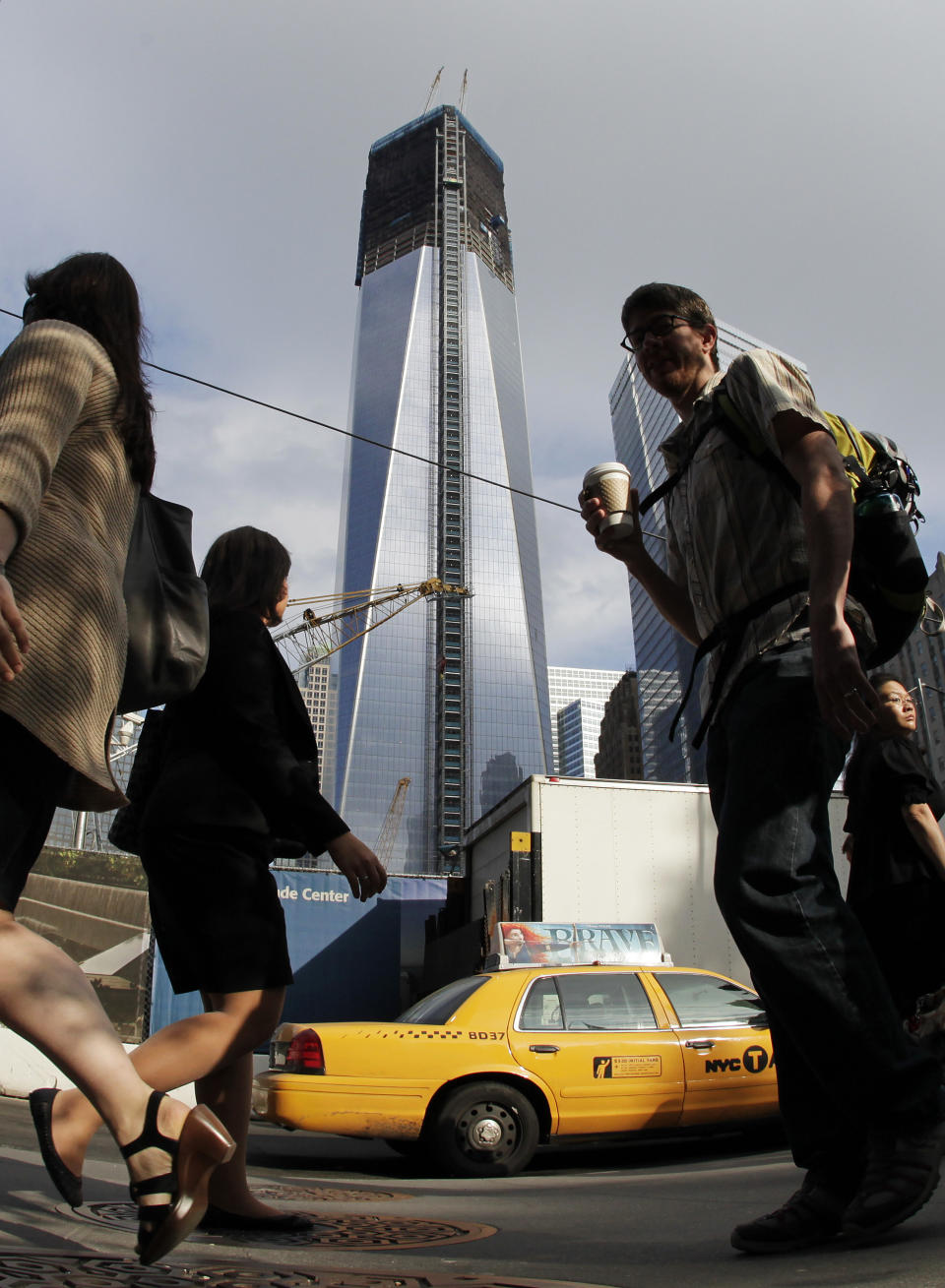 Commuters walk past the World Trade Center construction site and One World Trade Center, center, Thursday, June 14, 2012 in New York.  President Barack Obama is scheduled to visit the site later Thursday. World Trade Center PATH service will be suspended during Obama's visit and PATH trains from Newark will terminate at Grove Street in Jersey City.(AP Photo/Mark Lennihan)