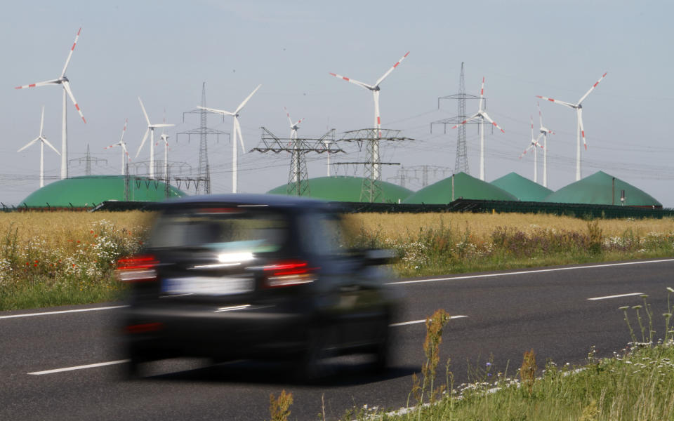 FILE - In this June 29, 2011 file photo a car passes by a a biogas plant and windmills near Nauen, Germany. The crisis in Ukraine is underlining the urgency of Germany's biggest political challenge as Chancellor Angela Merkel's new government marks 100 days in office Wednesday, March 26, 2014, getting the country's mammoth transition from nuclear to renewable energy sources on track. The transition started in earnest when Merkel, after Japan's 2011 Fukushima nuclear disaster, abruptly accelerated Germany's exit from nuclear power. Since then, the "Energiewende" _ roughly, "energy turnaround" _ has created increasing headaches. (AP Photo/Ferdinand Ostrop, File)