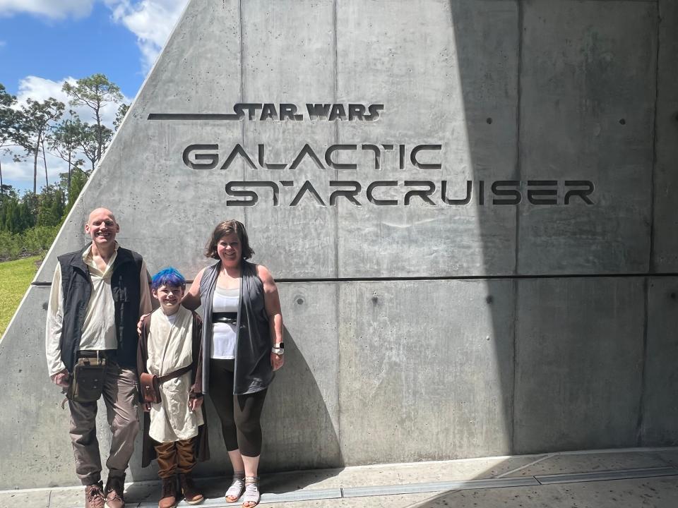 Catie and her family in costumes posing in front of the Star Wars Galactic Starcruiser sign