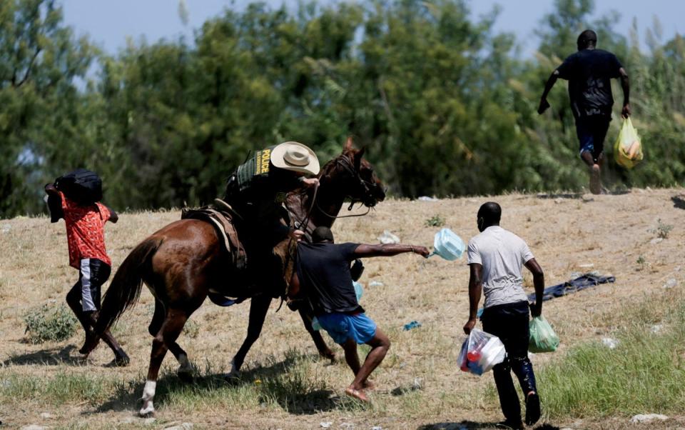 A U.S. border patrol officer grabs the shirt of a migrant trying to return to the United States along the Rio Grande river, after having crossed from the United States into Mexico to buy food, as seen from Ciudad Acuna, in Ciudad Acuna, Mexico September 19, 2021 (REUTERS)