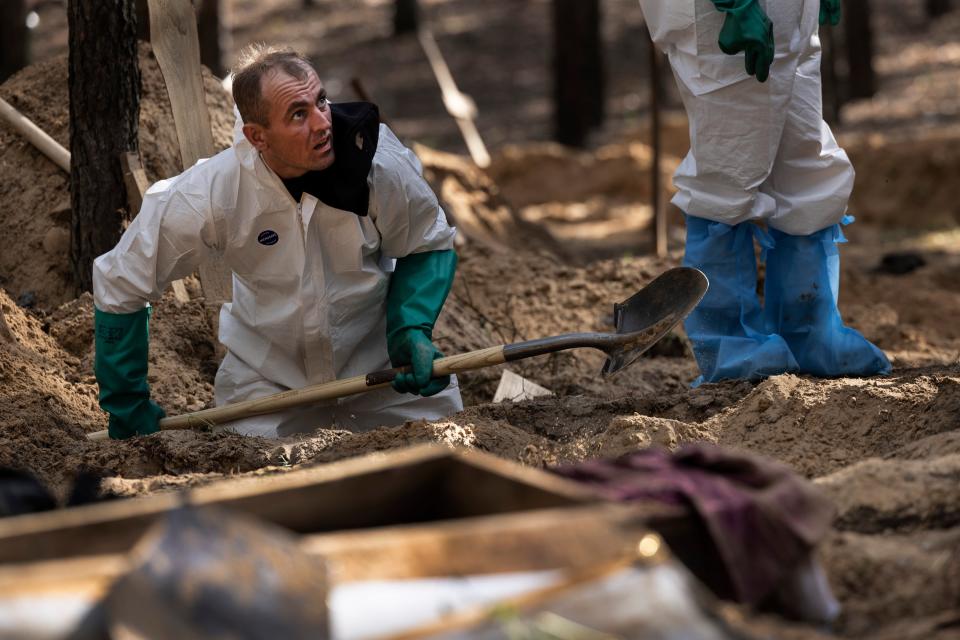 A Ukrainian rescue worker seen exhuming bodies from unidentified makeshift graves at the Pishanske cemetery (Getty Images)