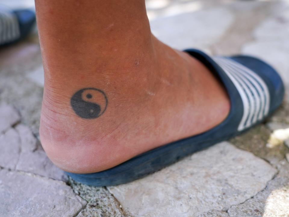 A man has the Chinese yin-and-yang symbol tattooed on his foot.