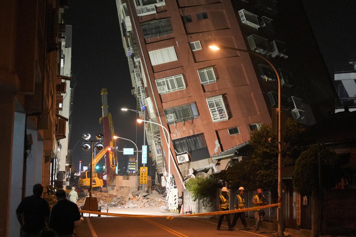 Workers walk at the site where a building collapsed, following an earthquake, in Hualien, Taiwan (REUTERS)