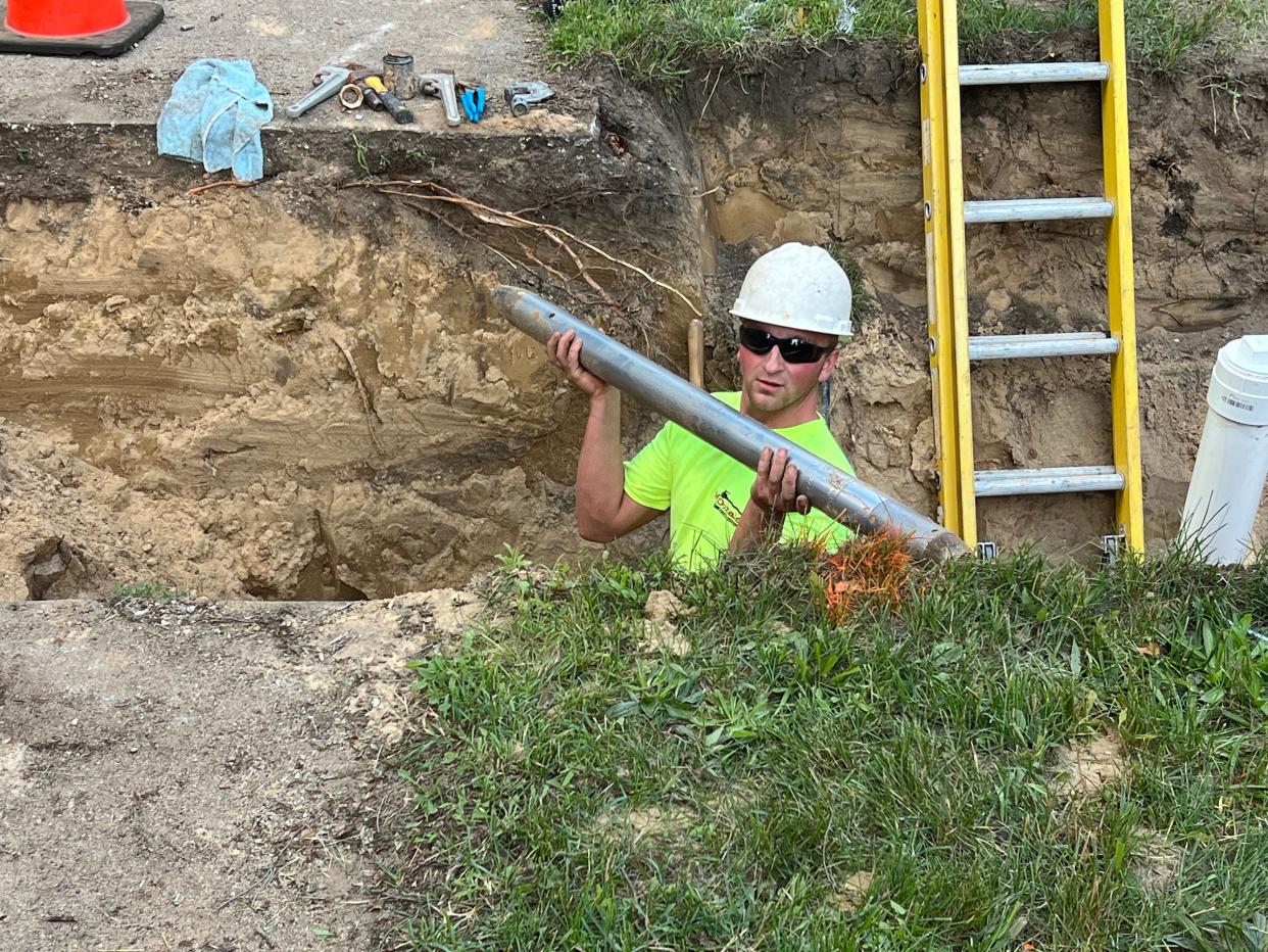 A crew member raises a component during a lead service line replacement on Wednesday, July 5, 2023, in Grand Rapids, Mich.