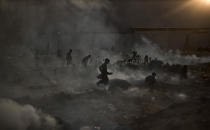 <p>Pakistani children, survey woods from a burning field, which was used by fruit and vegetable sellers to store their wooden boxes, on the outskirts of Islamabad, Pakistan, Nov. 4, 2013. (Photo: Muhammed Muheisen/AP) </p>