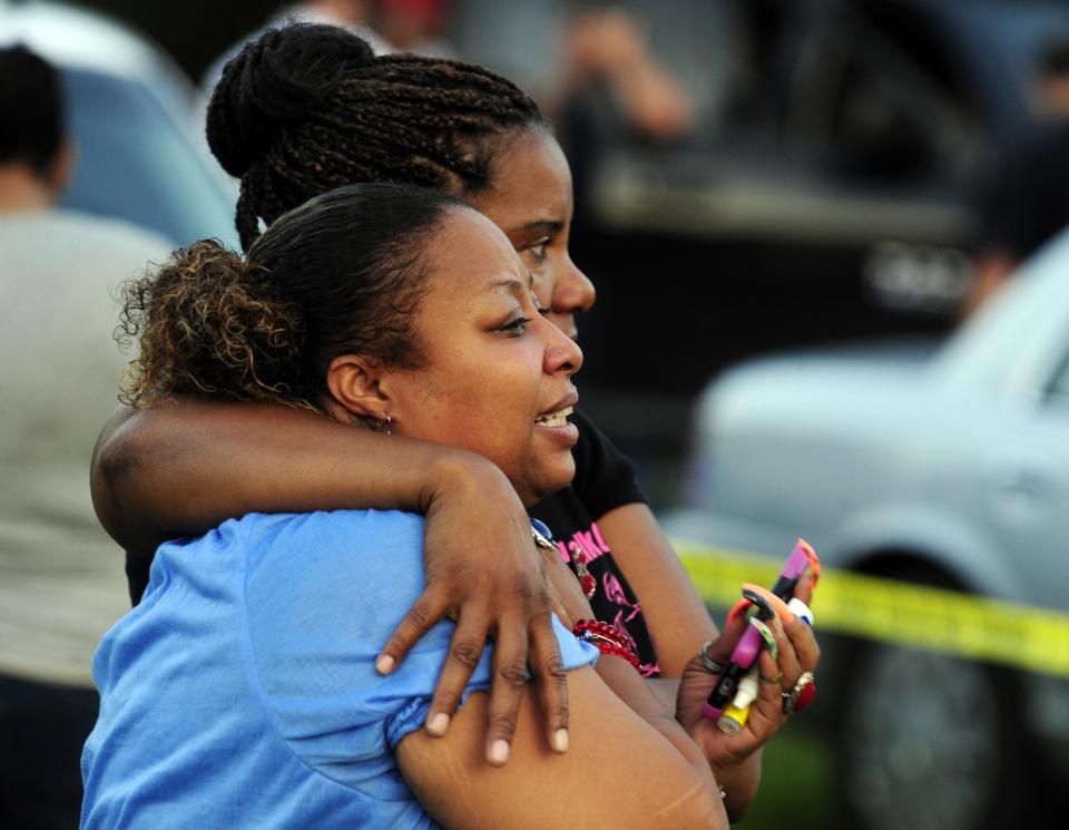 Tafara Hayes (front), and Rose Sonnier (back), who said they are the niece and cousin, respectively, of one of the victims, embrace as they watch police investigate the scene of a fatal stabbing and shooting at a home in Sunset, Louisiana, August 26, 2015. Police stormed a grocery market in a southwestern Louisiana town on Wednesday to arrest a man accused of stabbing two people and shooting an officer before barricading himself inside the store, the St. Landry Parish sheriff said. (REUTERS/Leslie Westbrook/The Advocate)