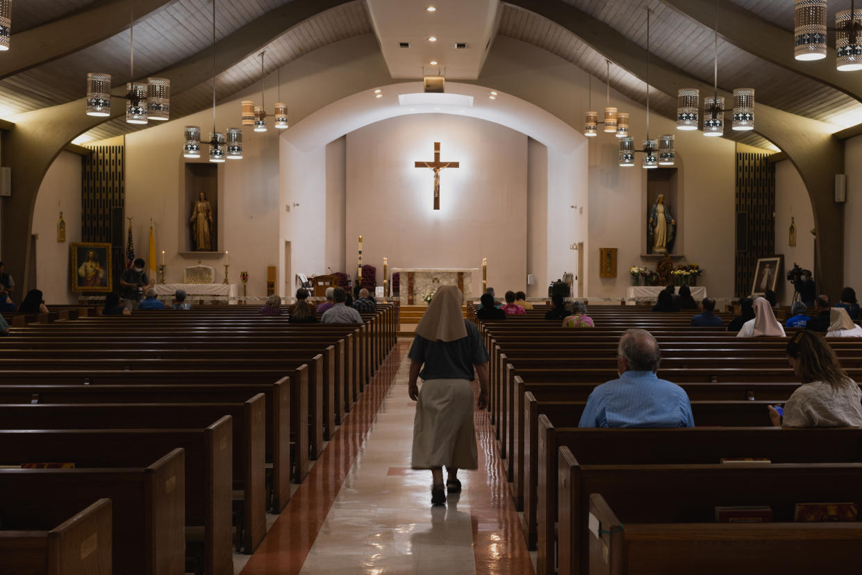 A nun walks down the aisle during Mass at Sacred Heart Catholic Church.