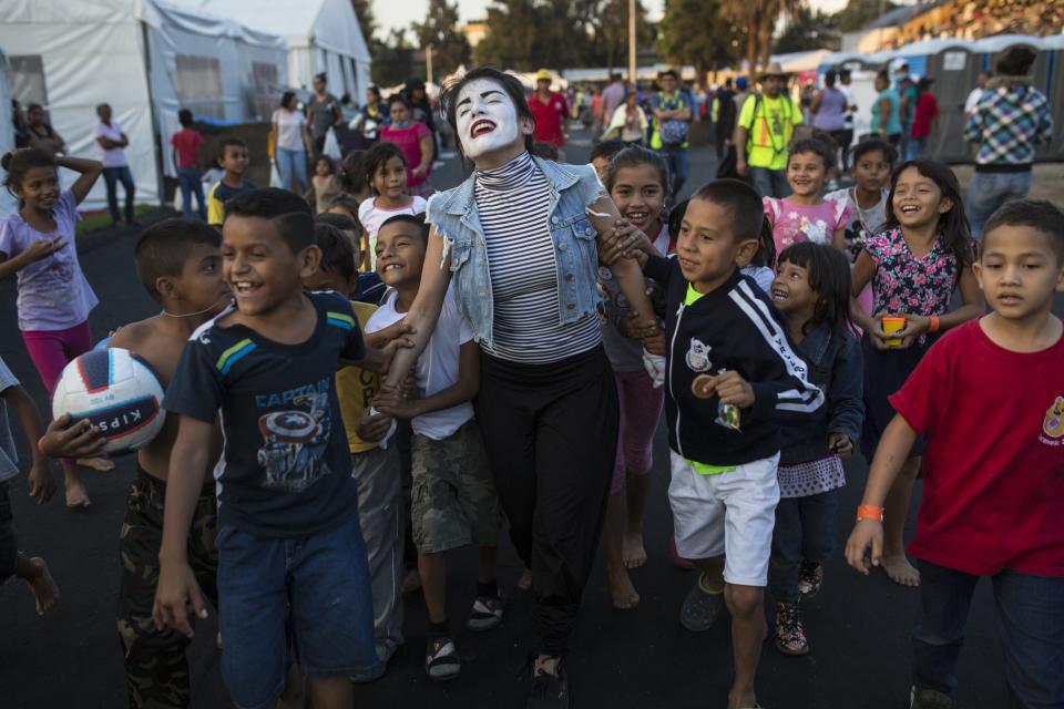 A woman performs as a mime for Central American migrant children at the Jesus Martinez stadium in Mexico City, Tuesday, Nov. 6, 2018. Humanitarian aid converged around the stadium in Mexico City where thousands of Central American migrants winding their way toward the United States were resting Tuesday after an arduous trek that has taken them through three countries in three weeks. (AP Photo/Rodrigo Abd)