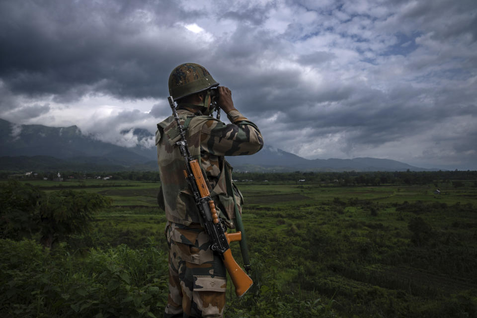 An Indian army soldier peers through binoculars as he monitors situation in nearby villages in Siden near Churachandpur, in the northeastern Indian state of Manipur, Tuesday, June 20, 2023. Two months since an ethnic conflict began, despite the army’s presence, hundreds of roadblocks and sandbag bunkers dot highways across the torn Manipur lands. Most of these imaginary borders are controlled by the warring communities. Those left unattended have been taken over by Indian forces who peep from binoculars into each side where armed bands in camouflage rev motorcycles. (AP Photo/Altaf Qadri)