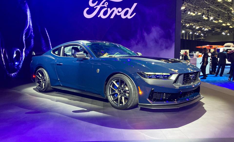 The Ford Mustang Dark Horse muscle car in dark blue against a dark backdrop.
