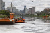 Men work on a cleaning river project where foam blankets a portion of the Pinheiros River in Sao Paulo, Brazil, Thursday, Oct. 22, 2020. Affected by domestic sewage and solid wastes discharges for years, Sao Paulo's state government is again trying to clean the Pinheiros River, considered one of the most polluted in Brazil. (AP Photo/Andre Penner)