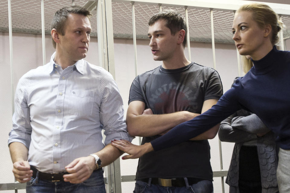 FILE - In this Tuesday, Dec. 30, 2014 file photo, Russian opposition activist Alexei Navalny's wife Yulia, right, and his brother Oleg Navalny, center, comfort Alexei at a court in Moscow, Russia. Moscow is bracing for more protests seeking the release of jailed opposition leader Alexei Navalny, who faces a court hearing Tuesday. Navalny was jailed last month and faces years in prison. Tens of thousands filled the streets across the vast country Sunday for a second straight weekend calling for his freedom, with thousands of arrests in the largest outpouring of discontent in Russia in years. (AP Photo/Pavel Golovkin, File)