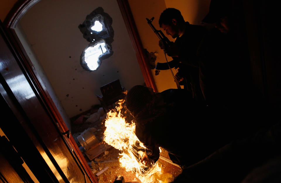 <p>Libyan rebel fighters carry out a comrade wounded during an effort to dislodge some ensconced government loyalist troops who were firing on them from a building (background) during house-to-house fighting on Tripoli Street in downtown Misrata April 20, 2011 in Misrata, Libya. (Photo by Chris Hondros/Getty Images) </p>