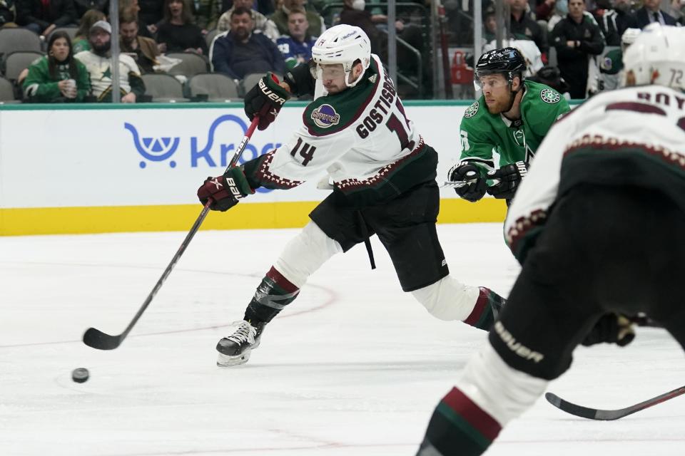 Arizona Coyotes defenseman Shayne Gostisbehere (14) shoots and scores as Dallas Stars center Joe Pavelski, right, defends in the second period of an NHL hockey game in Dallas, Monday, Dec. 6, 2021. (AP Photo/Tony Gutierrez)