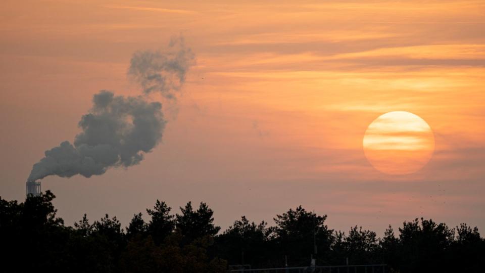 Die Sonne geht neben einem rauchenden Schornstein unter. Die Grenzwerte für den Ausstoß von Schadstoffen aus vielen Industrieanlagen werden strenger.