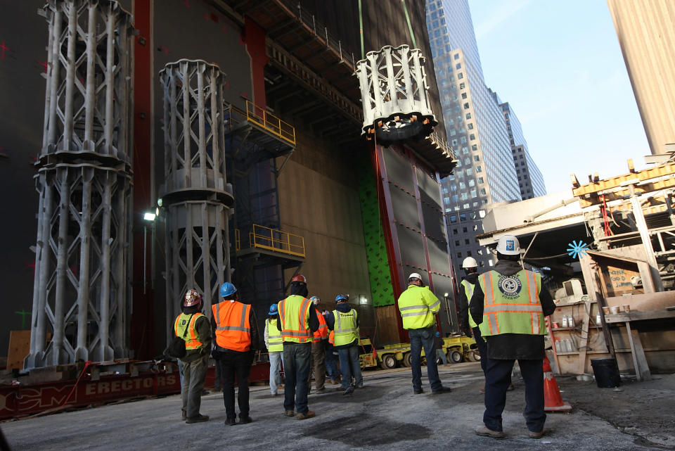 Workers watch as the first piece of the spire is hoisted atop One World Trade Center on December 12, 2012 in New York City. The first of 18 sections of spire was hoisted atop the 104-story building by crane this morning. (Photo by Mario Tama/Getty Images)