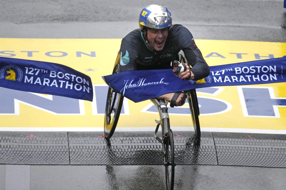 Marcel Hug, of Switzerland, breaks the tape to win the men's wheelchair division of the Boston Marathon, Monday, April 17, 2023, in Boston. (AP Photo/Charles Krupa)