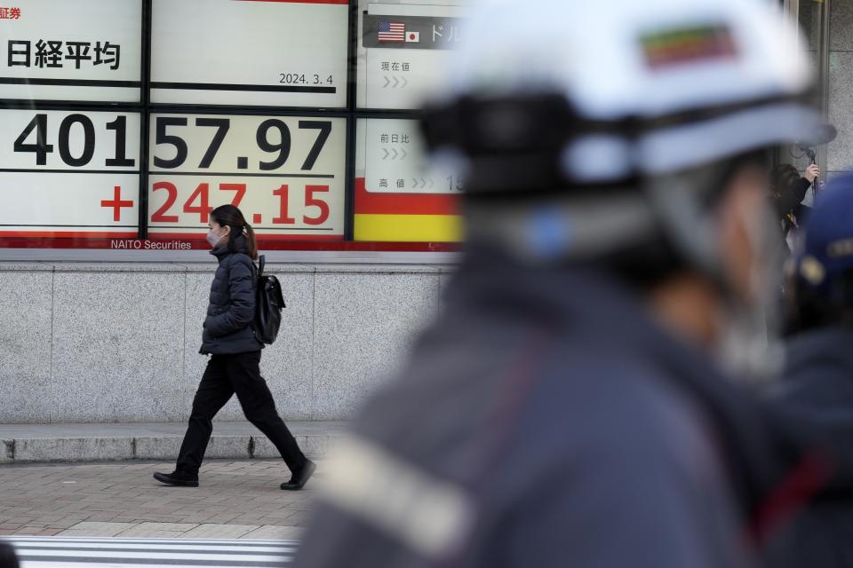 A person walks in front of an electronic stock board showing Japan's Nikkei 225 index at a securities firm Monday, March 4, 2024, in Tokyo. Japan's Nikkei 225 share benchmark has topped 40,000 for the first time as strong demand for technology shares keeps pushing the index higher.(AP Photo/Eugene Hoshiko)