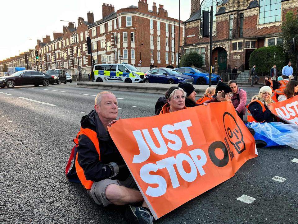 Activists of Just Stop Oil climate campaign group hold a banner at Barons Court in west London as they block the A4 (AFP via Getty Images)