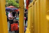 People wearing face masks are seen behind barricades at a market following the coronavirus disease (COVID-19) outbreak in Wuhan