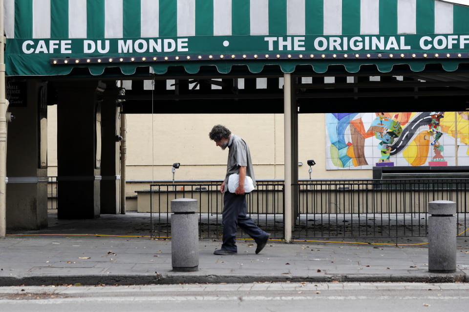 FILE - In this Friday, March 27, 2020, file photo, a man walks past the closed Cafe Du Monde restaurant in the French Quarter of New Orleans. President-elect Joe Biden will inherit a mangled U.S. economy, one that never fully healed from the coronavirus and could suffer again as new infections are climbing. The once robust recovery has shown signs of gasping after federal aid lapsed. Ten million remain jobless and more layoffs are becoming permanent. The Federal Reserve found that factory output dropped. (AP Photo/Gerald Herbert, File)