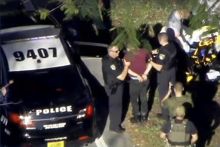 A man placed in handcuffs is led by police near Marjory Stoneman Douglas High School following a shooting incident in Parkland, Florida, U.S. February 14, 2018 in a still image from video. WSVN.com via REUTERS.