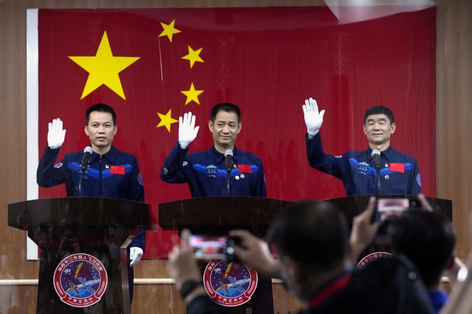 Chinese astronauts, from left, Tang Hongbo, Nie Haisheng, and Liu Boming wave at a press conference at the Jiuquan Satellite Launch Center ahead of the Shenzhou-12 launch from Jiuquan in northwestern China, Wednesday, June 16, 2021. China plans on Thursday to launch three astronauts onboard the Shenzhou-12 spaceship, who will be the first crew members to live on China's new orbiting space station Tianhe, or Heavenly Harmony from the Jiuquan Satellite Launch Center in northwest China. (AP Photo/Ng Han Guan)