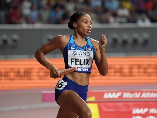 Allyson Felix sprints with a baton in hand and bib numbers with her last name and the number 6