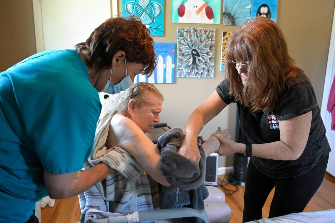 Shelly Rea, left, of Harbor Hospice, assists Carol Dowell as they bathe Ellen DeFoe at Dowell’s home in Kansas City. Since March 2019, Dowell has been providing 24/7 care for DeFoe, who has late-stage Alzheimer’s disease.