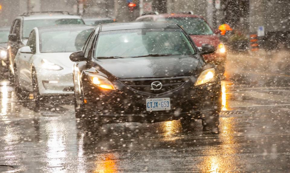 Cars lined up at Front and Simcoe streets during the wet snowfall on March 29, 2023.