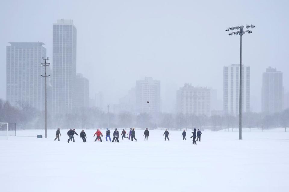 Men play football on a soccer field in Chicago's Lincoln Park Wednesday, Feb. 2, 2022. A major winter storm with millions of Americans in its path brought a mix of rain, freezing rain and snow to the middle section of the United States as airlines canceled hundreds of flights, governors urged residents to stay off roads and schools closed campuses.