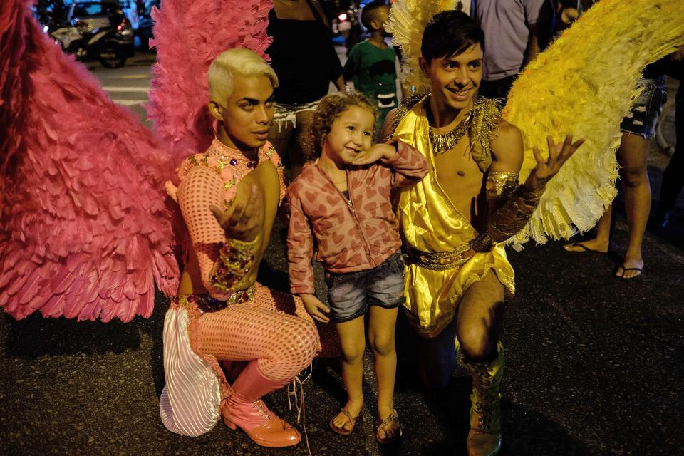 Revelers pose for a picture with a young girl during the 2nd LGBT Pride parade at Alemao favela in Rio de Janeiro, Brazil, on September 28, 2014. AFP PHOTO / YASUYOSHI CHIBA