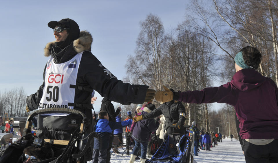 Iditarod rookie Richie Beattie, left, looks ahead as he greets a fan on the trail during the ceremonial start of the Iditarod Trail Sled Dog Race Saturday, March 2, 2019, in Anchorage, Alaska. (AP Photo/Michael Dinneen)