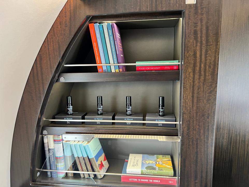 A bookshelf with books and de Mamiel sleep oils on board a VistaJet Bombardier Global 7500