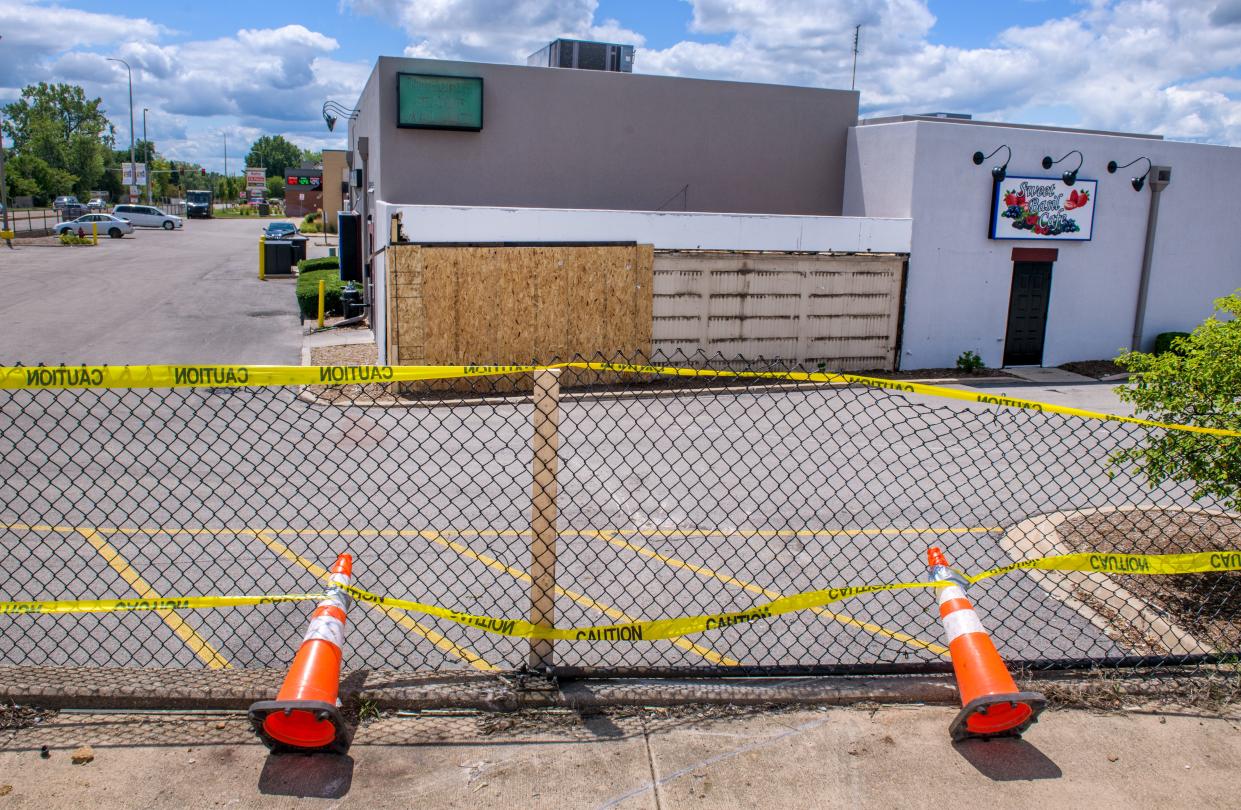 Caution tape covers an area of fencing damage in a traffic accident Wednesday, July 17, 2024 near the Sweet Basil Cafe in the Sheridan Village shopping center in Peoria. A collision at the intersection of intersection of West Lake Avenue and North Sheridan Road caused a commercial truck to go down the embankment and crash into the business.