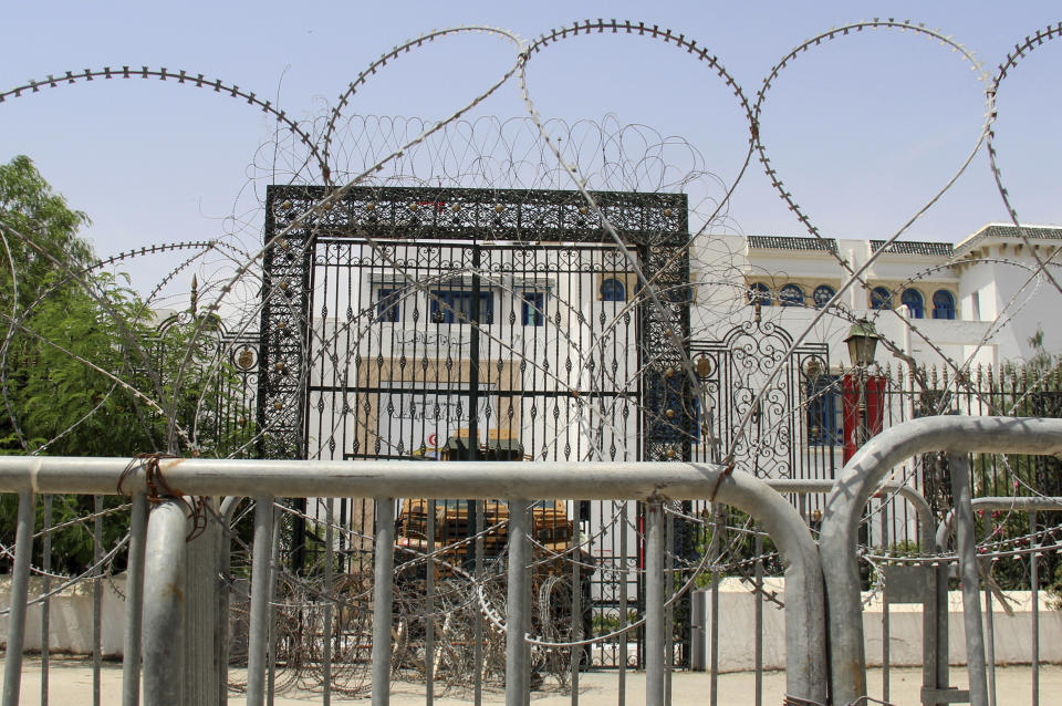 Barbed wire and a military armored personnel carrier block a side entrance of the Tunisian parliament in Tunis, Tuesday, July 27, 2021. The Ennahda party, has called for dialogue, following President Kais Saeid's sacking of the prime minister and suspension of parliament on Sunday. (AP Photo/Hassene Dridi)