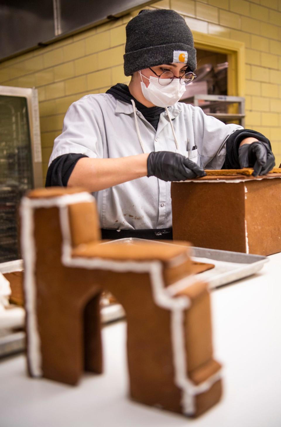 Rocket Baucco works on building Indiana University structures while creating a sprawling gingerbread scene under the direction of Chef Hayden Kemerly at the Indiana Memorial Union on Tuesday, Nov. 29, 2022. The finished candy creation will be on display Thursday night for the Light Up The Night lighting ceremony. 