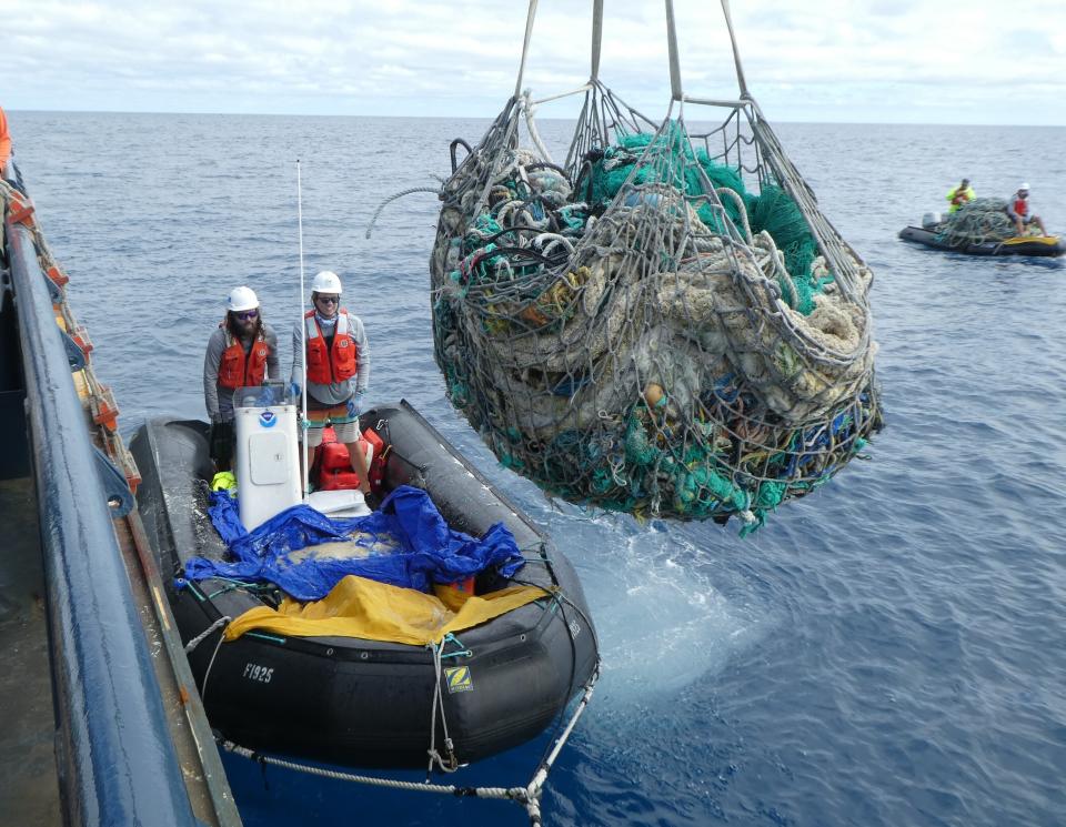 In this April 11, 2021 photo provided by Matt Saunter, Joao Garriques, left, and Matthew Chauvin load fishing nets onto a ship near Kure Atoll in the Northwestern Hawaiian Islands. A crew has returned from the remote Northwestern Hawaiian Islands with a boatload of marine plastic and abandoned fishing nets that threaten to entangle endangered Hawaiian monk seals and other marine animals on the tiny, uninhabited beaches stretching for more than 1,300 miles north of Honolulu. (Matt Saunter, Papahanaumokuakea Marine Debris Project via AP)