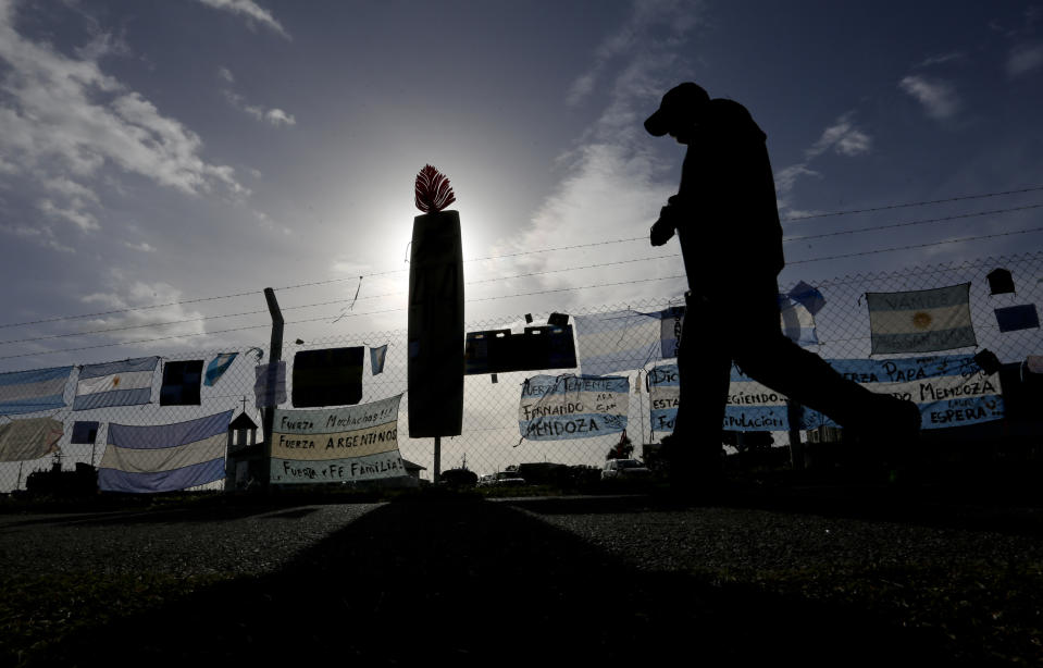 <p>Un hombre camina cerca de banderas argentinas y pancartas colgadas en una valla en la base naval en Mar del Plata, Argentina, el martes 21 de noviembre de 2017, en apoyo de la tripulación de un submarino perdido. El submarino argentino ARA San Juan se ha perdido en el mar desde el miércoles 15 de noviembre con 44 tripulantes a bordo. (AP Foto / Vicente Robles) </p>