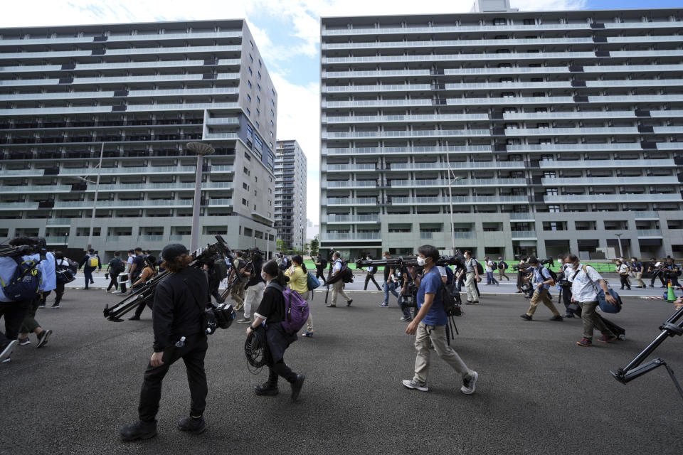 Journalists walk on a road during a press tour of the Tokyo 2020 Olympic and Paralympic Village Sunday, June 20, 2021, in Tokyo. (AP Photo/Eugene Hoshiko)