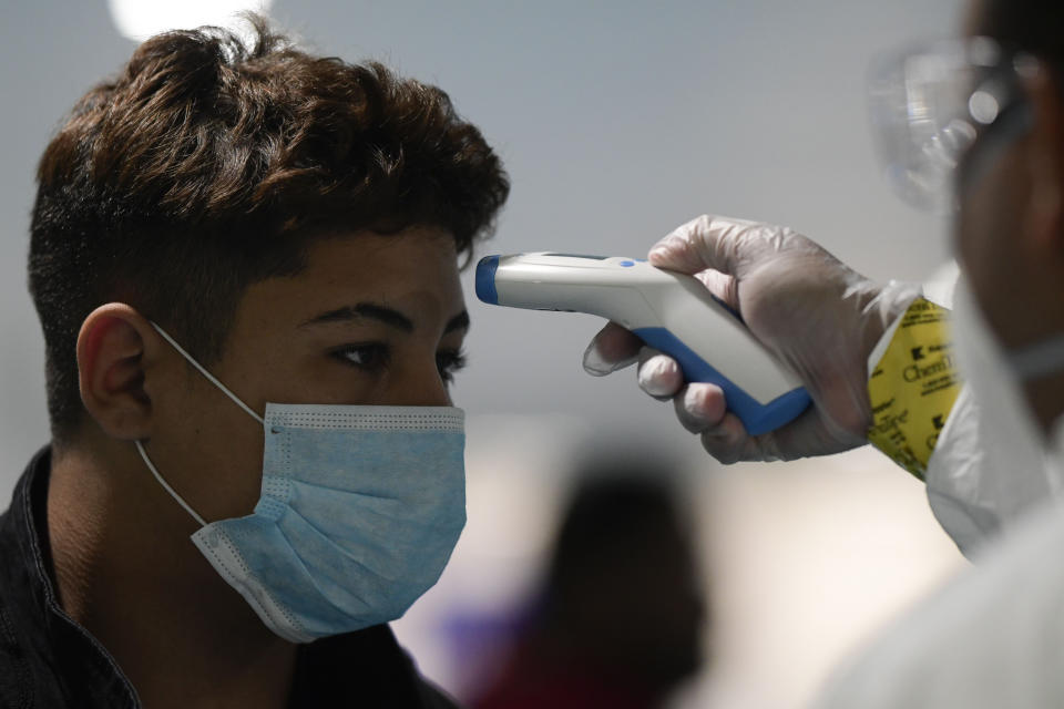 National Guard personnel carry out bio screening on arriving passengers at the Luis Muñoz Marin Airport in an effort to detect and isolate the new coronavirus, in Carolina, Puerto Rico, Tuesday, March 17, 2020. (AP Photo/Carlos Giusti)