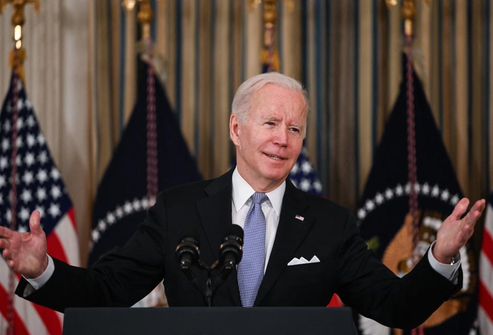 President Biden delivers remarks at a podium in front of American and presidential flags and a curtain backdrop.