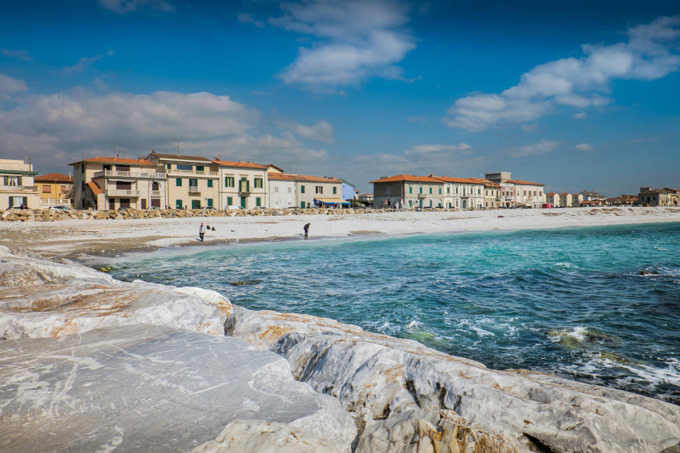 Seaside with white rocky foreground, buildings along the shore, and people at a distance