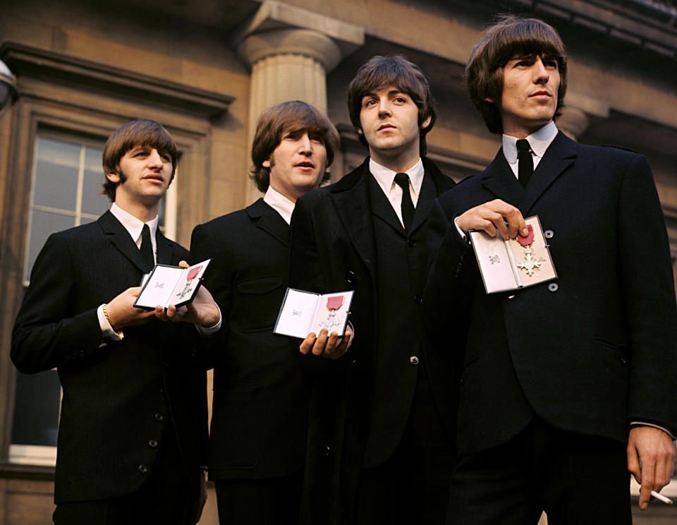 The Beatles showing their MBE Insignias in the forecourt after receiving them from the Queen. (l-r) Ringo Starr, John Lennon, Paul McCartney and George Harrison.
