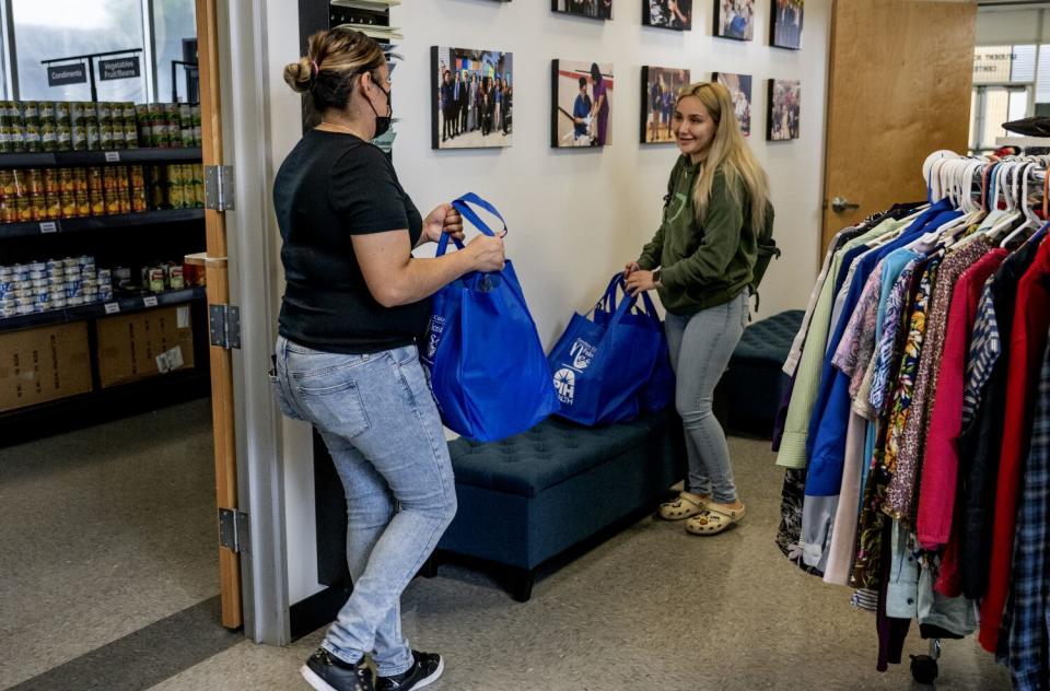 A female student is given two bags of groceries from a campus center.