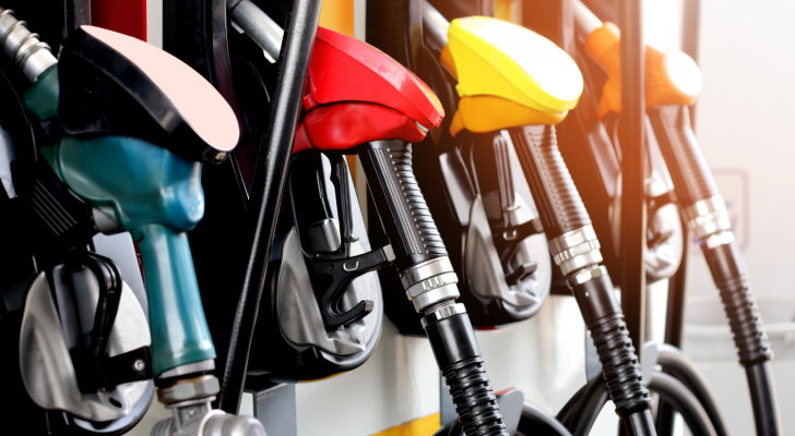 A photo of a row of gasoline pump handles at a pump with the sun shining on them. Gas prices dropping.